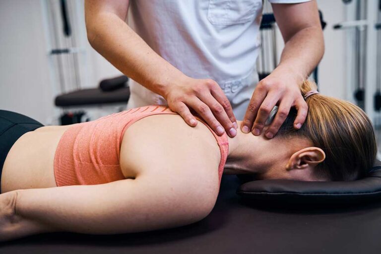 A person receiving a gentle chiropractic adjustment on a therapy table in a bright, welcoming treatment room.
